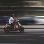 Man rijdt op duurdere elektrische step door stedelijke omgeving