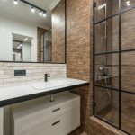 Moderne badkamer met trendy spots en railverlichting systeem boven spiegel en douche voor optimale verlichting