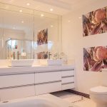 Moderne badkamer met sfeervolle inrichting: kunststof panelen, groene planten, warme verlichting en houten accessoires